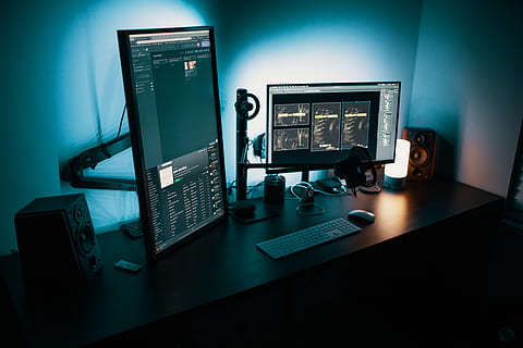 Dual monitors on a desk with codes in them