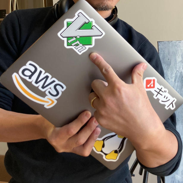 Takeo holding a Macbook Pro and indicating a Vim sticker on it